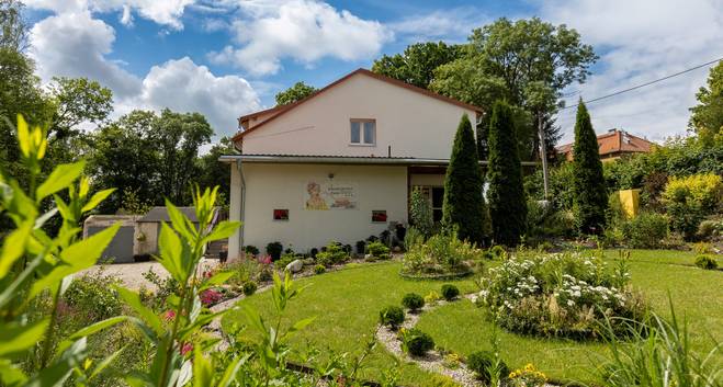 Pokoje po drodze - komfortowy nocleg w Barczewie. Widok na budynek obiektu otoczony zielonym ogrodem